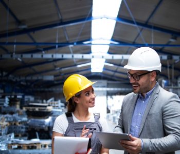 Manager supervisor and worker discussing about production results and new strategy in factory industrial hall.